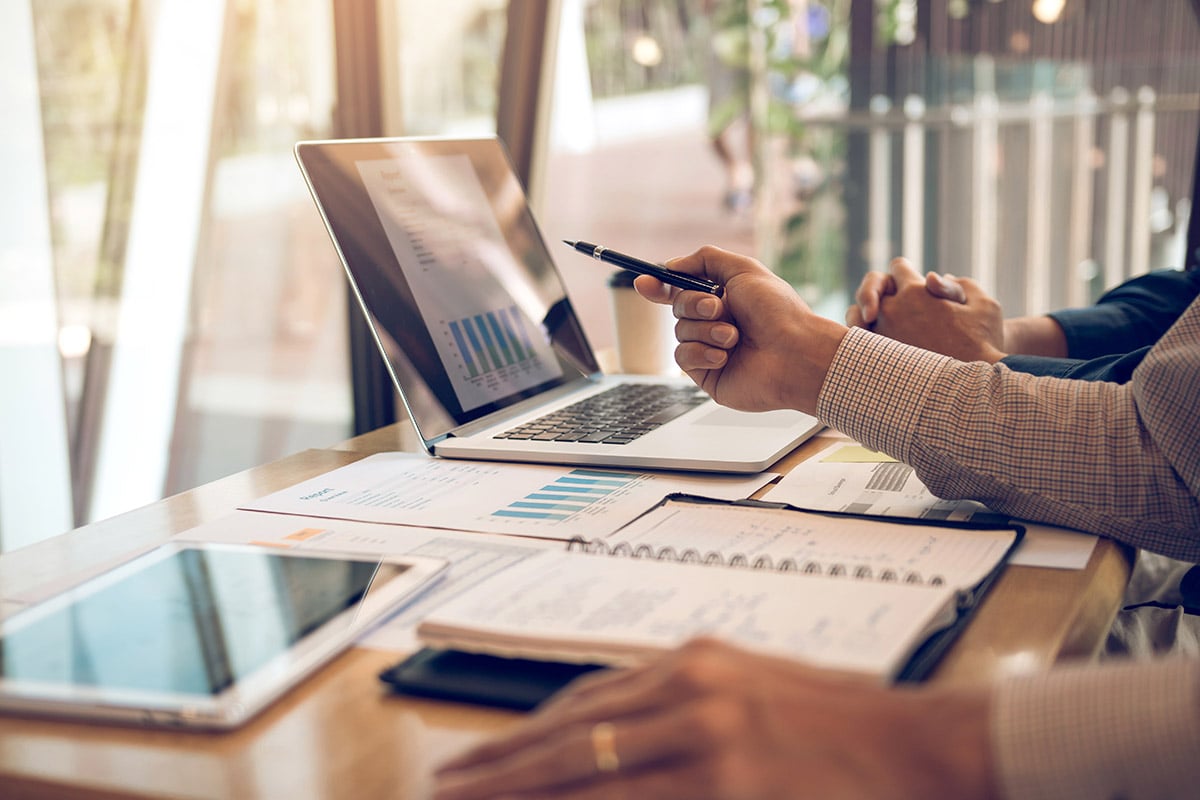 person pointing to laptop with charts on it