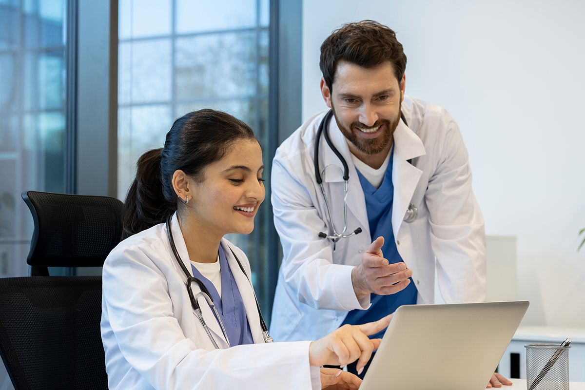 Two doctors, a man and a woman, collaborate at a desk in a modern office. 